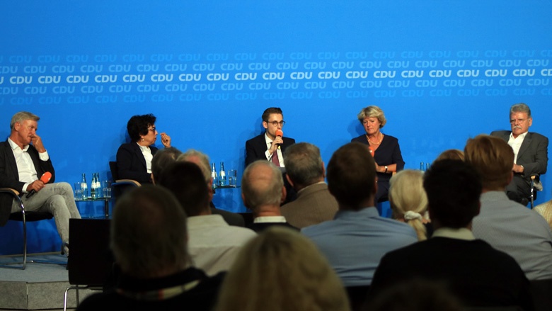 Kevin Hänel moderiert die Debatte. Auf dem Bild sieht man das Podium. Kevin Hänel moderiert die Debatte.